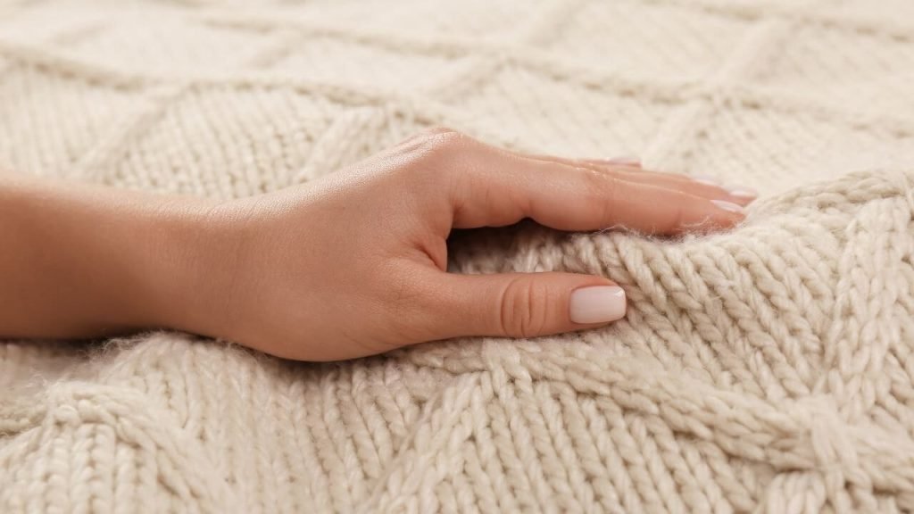 A hand gently touching a soft, knitted cotton fabric