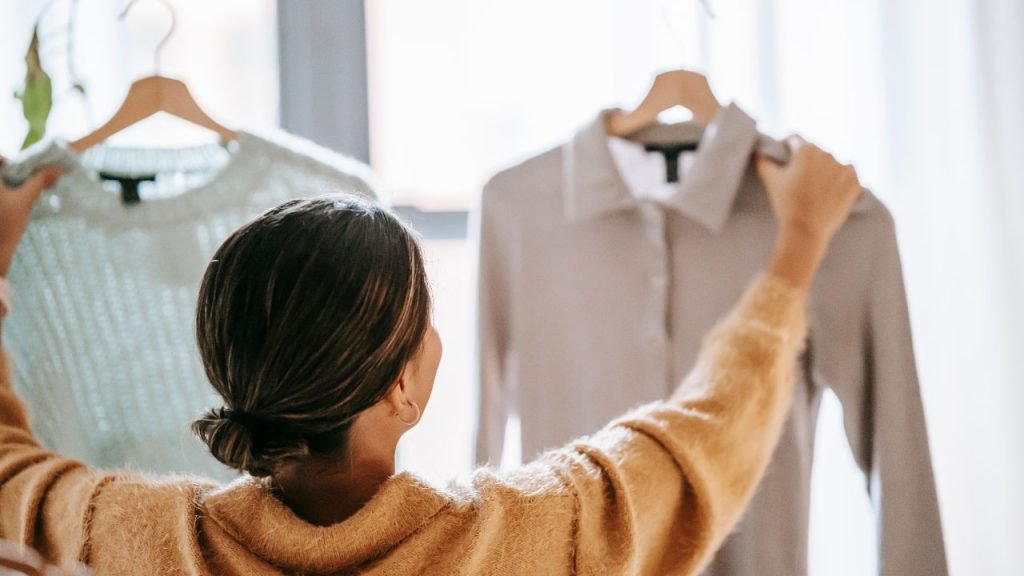 A woman choosing between 2 types of clothing.