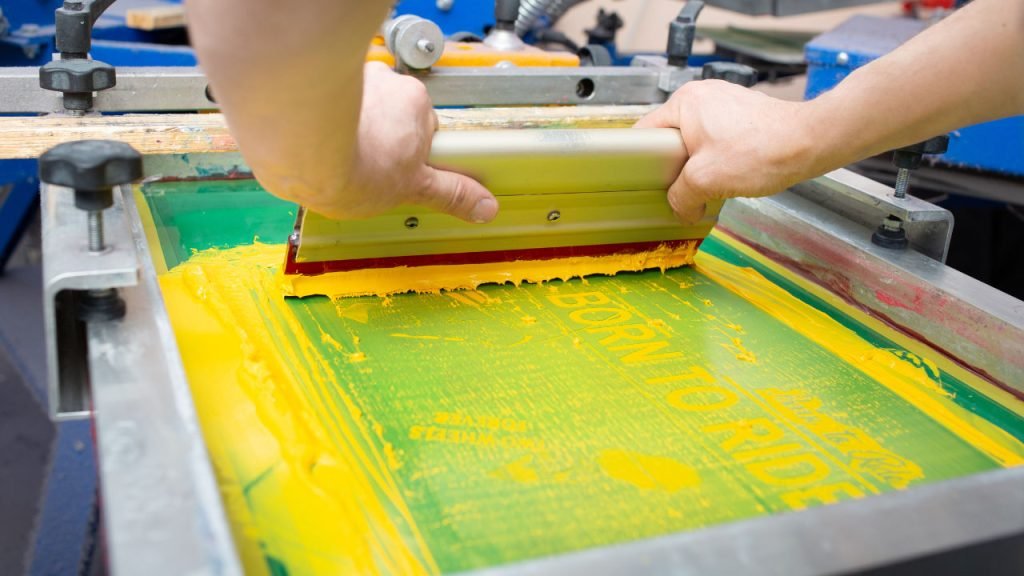 A yellow paint run through a mesh during screen printing process.