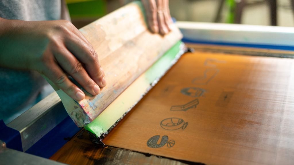 Ink being run through a mesh during screen printing.